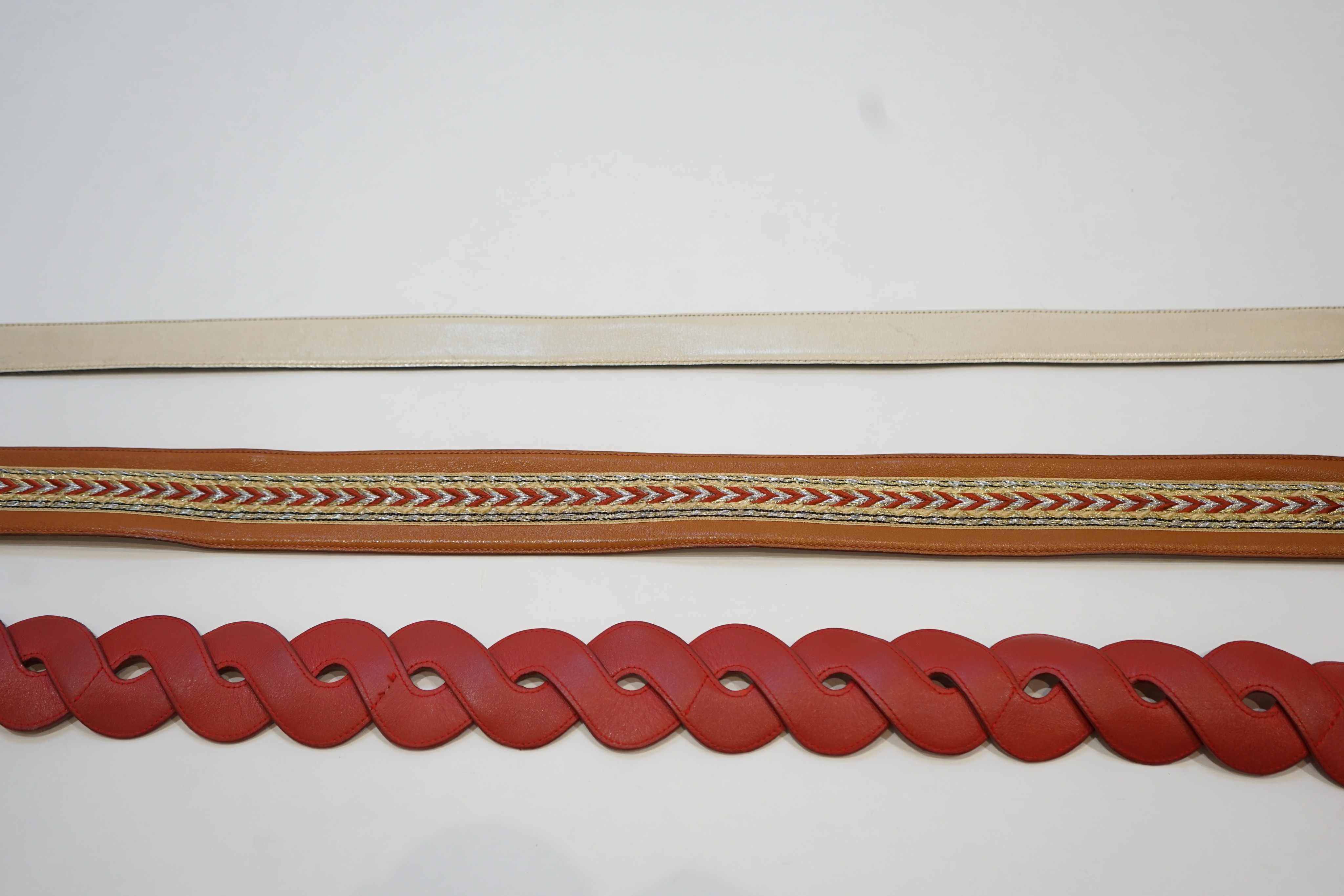 A Gucci cream leather belt and two Valentino belts